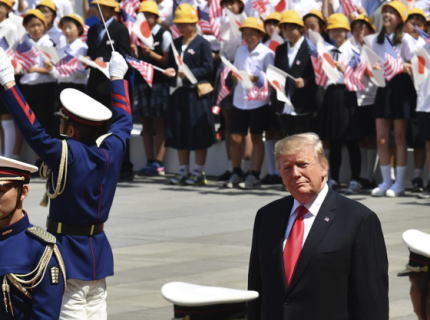 朝日新聞「皇居・宮殿東庭で開かれたトランプ米大統領の歓迎行事にて日章旗と星条旗を振って出迎えた小学生達、旗振り役の児童達は『名誉』か『動員』か」